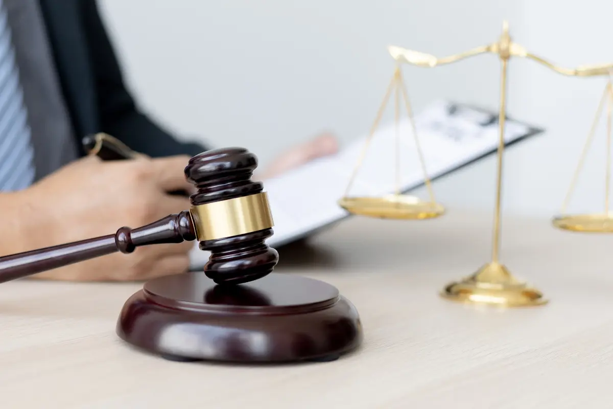 Judge’s gavel and golden weighing scale placed on a table in a courtroom setting, representing legal proceedings